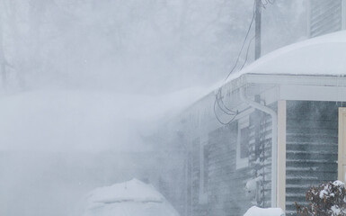 Snow blowing off a roof during a blizzard creating white out conditions