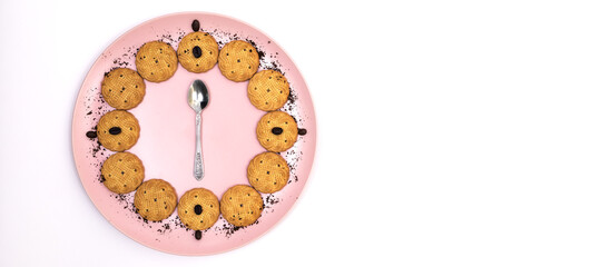 Some cookies served on a pink plate with coffee sprinkles with a teaspoon in the center on a white...