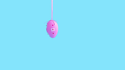 Easter pink egg hanging on a ribbon on a blue background. Copy space
