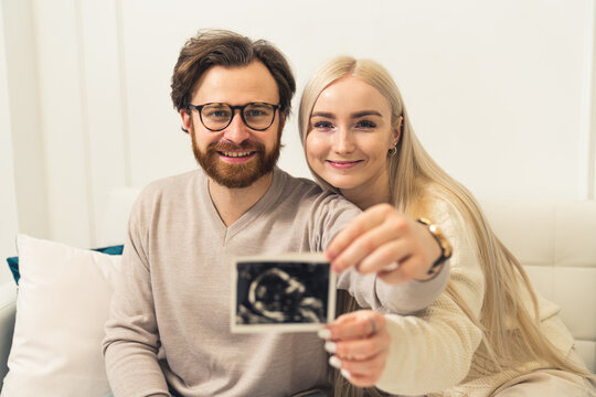 Happy caucasian married couple showing pregnancy ultrasound picture of their unborn baby. . High quality photo