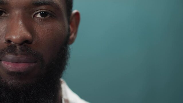 A young black man in a white shirt is looking at the camera seriously 