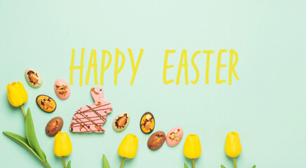 Easter composition with spring flowers tulips Easter chocolate eggs and rabbit, pastel background