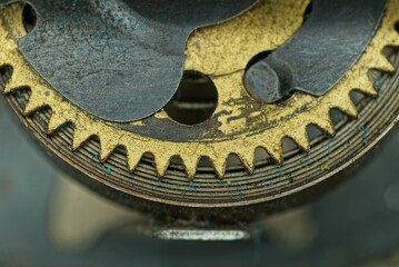 part of the mechanism of an old clock made of yellow dirty copper springs and gears