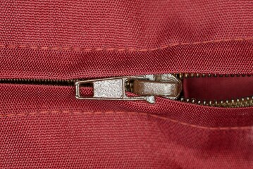 one brown metal open zip on a red fabric of clothing 