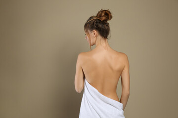 Back view of woman with perfect smooth skin on beige background. Beauty and body care
