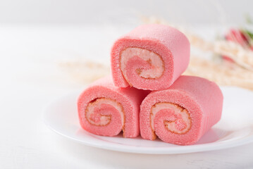 Obraz na płótnie Canvas Pink strawberry roll cake or swiss roll with whipped cream and strawberry flavor on white background