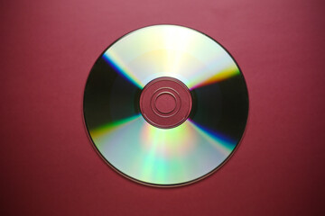 Compact disk close-up on a red burgundy background, outdated data storage