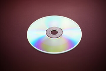 Compact disk close-up on a red burgundy background, outdated data storage