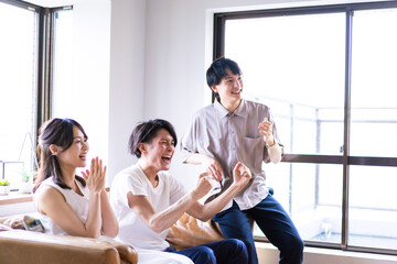 Fototapeta premium 家でスポーツの試合を観戦する若い男女