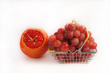 Ripe red grapes and pomegranate fruits on a white background. Still life, ripe fruits, red large grapes and pomegranate isolated, close-up. Place for an inscription.