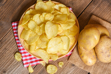 Potato chips snack on plate top view, Crispy potato chips on the kitchen table and fresh raw potatoes