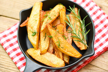 Potato wedges on plate with rosemary herb, Cooking french fries or fry potatoes
