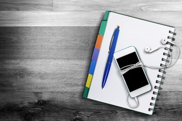 Bible, journal, cell phone on a dark wood desk
