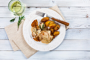 Rabbit Meat With Rosemary in Sour Cream Sauce and Potato on White Wooden Background. Selective focus.