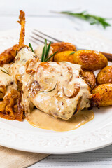 Rabbit Meat With Rosemary in Sour Cream Sauce and Potato on White Wooden Background. Selective focus.