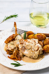 Rabbit Meat With Rosemary in Sour Cream Sauce and Potato on White Wooden Background. Selective focus.