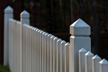 Closeup orf a white picket fence with a fence