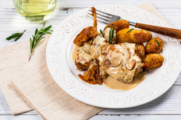 Rabbit Meat With Rosemary in Sour Cream Sauce and Potato on White Wooden Background. Selective focus.