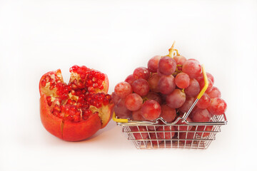 Ripe red grapes and pomegranate fruits on a white background. Still life, ripe fruits, red large grapes and pomegranate isolated, close-up. Place for an inscription.