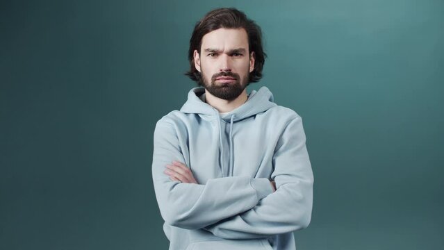 Isolated Dark-haired guy confused feels doubt while makes choice, dressed in casual hoodie