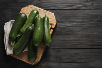 Raw ripe zucchinis on black wooden table, top view. Space for text