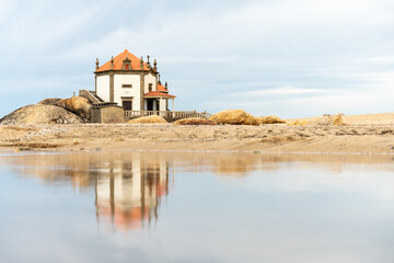 chapel in the middle of the beach next to the water of Senhor da Pedra in Miramar, Portugal.
