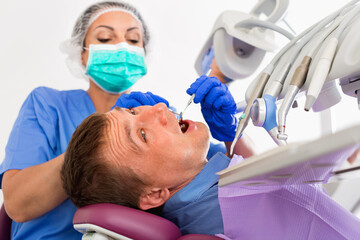 efficient positive dentist checking teeth of patient male sitting in medical center