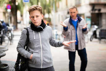 Upset teenage boy making stop gesture to dissatisfied bypasser moralizing him outdoors