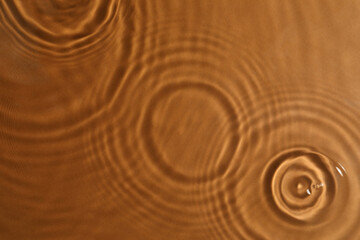 Closeup view of water with circles on brown background