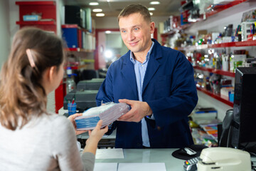 Positive administrator of the printing house gives finished product to the buyer. High quality photo