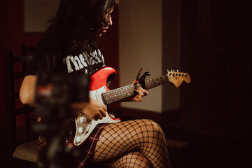 Mujer guitarrista tocando la guitarra y grabandose
