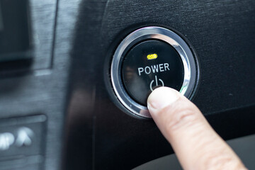 finger on a power button to push start the car engine