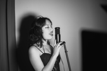 Mujer joven cantando contenta en un estudio musical a blanco y negro