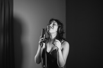 Mujer joven cantando contenta en un estudio musical a blanco y negro