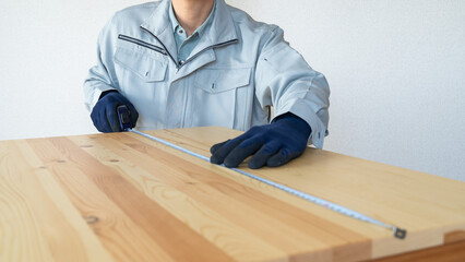 作業服の男性｜木材の寸法を測る - obrazy, fototapety, plakaty