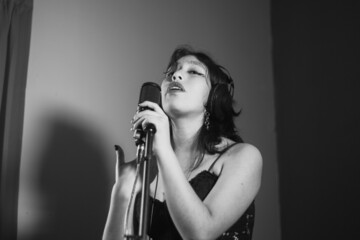 Mujer joven cantando contenta en un estudio musical a blanco y negro