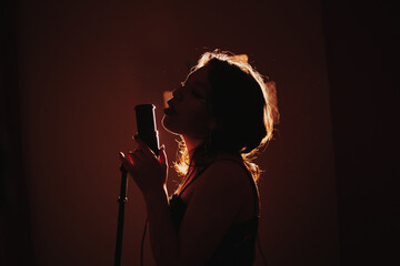 silueta de Joven cantante apasionada a contraluz