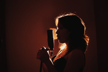 silueta de Joven cantante apasionada a contraluz