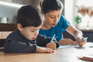 The mother spent the afternoon sitting in the kitchen with her son and checking the homework. Mom help boy learning, great design for any purposes.