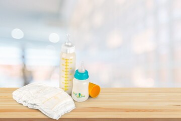 Bottles of milk for baby with toys on table in kitchen background