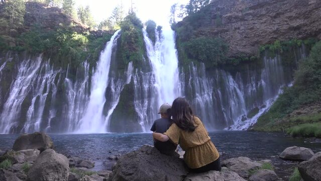 Burney Falls in Shasta County, mom and child sitting in front of the cascading waterfall.