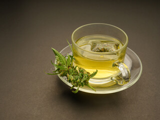 Cannabis tea in a teacup and marijuana buds flower on a gray background