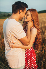 Couple standing close to each other in the wheat field away from the city, following a kiss. Nature landscape. People lifestyle concept.