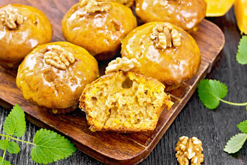 Cupcake pumpkin with orange glaze and walnuts on brown board