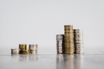 stacks of different coins divided between a small and a big group on white background, good vs bad...