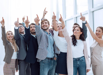 Fototapeta na wymiar group of happy young business people pointing upwards