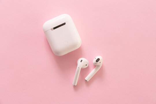 NAKHONRATCHASIMA, THAILAND - APRIL 10, 2020: Apple AirPods wireless Bluetooth headphones and charging case for Apple iPhone on a pink background.