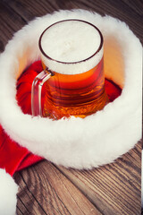 mug of beer with Santa's hat on wooden background