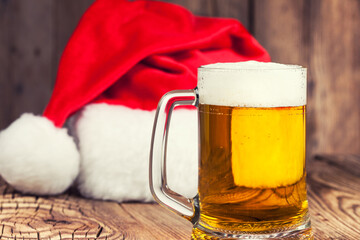 mug of beer with Santa's hat on wooden background