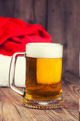 mug of beer with Santa's hat on wooden background